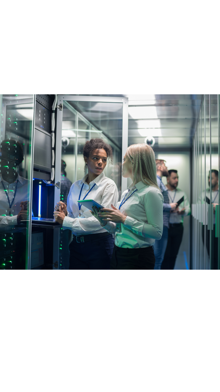 Two female professionals discussing technology in a server room, with one holding a tablet, overlaid with BDO branding and messaging on AI governance and assurance.