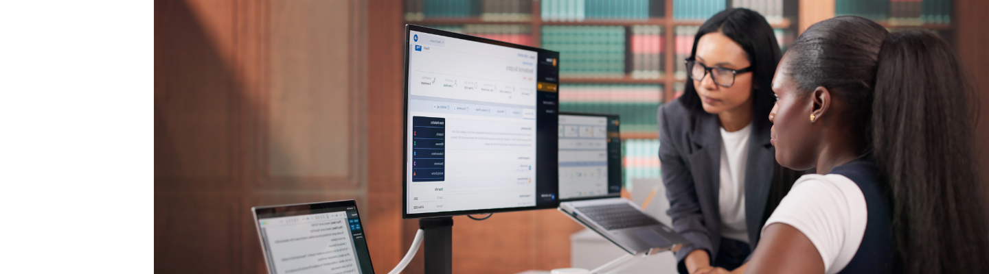 Two business professionals reviewing documents and computer screens together in an office.