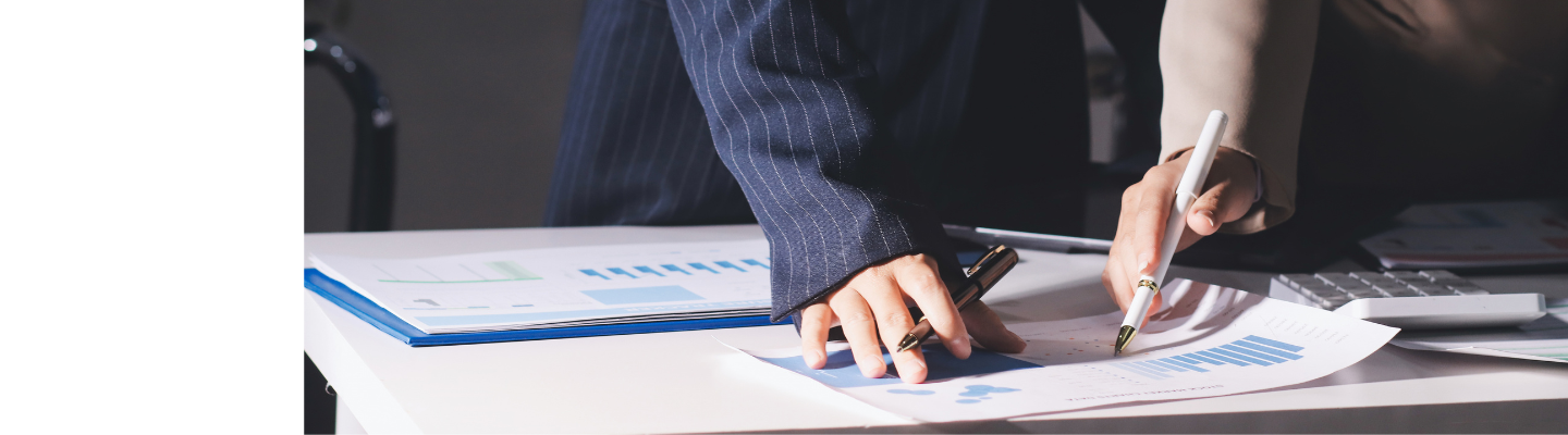 Two professionals reviewing financial charts and documents at a desk.