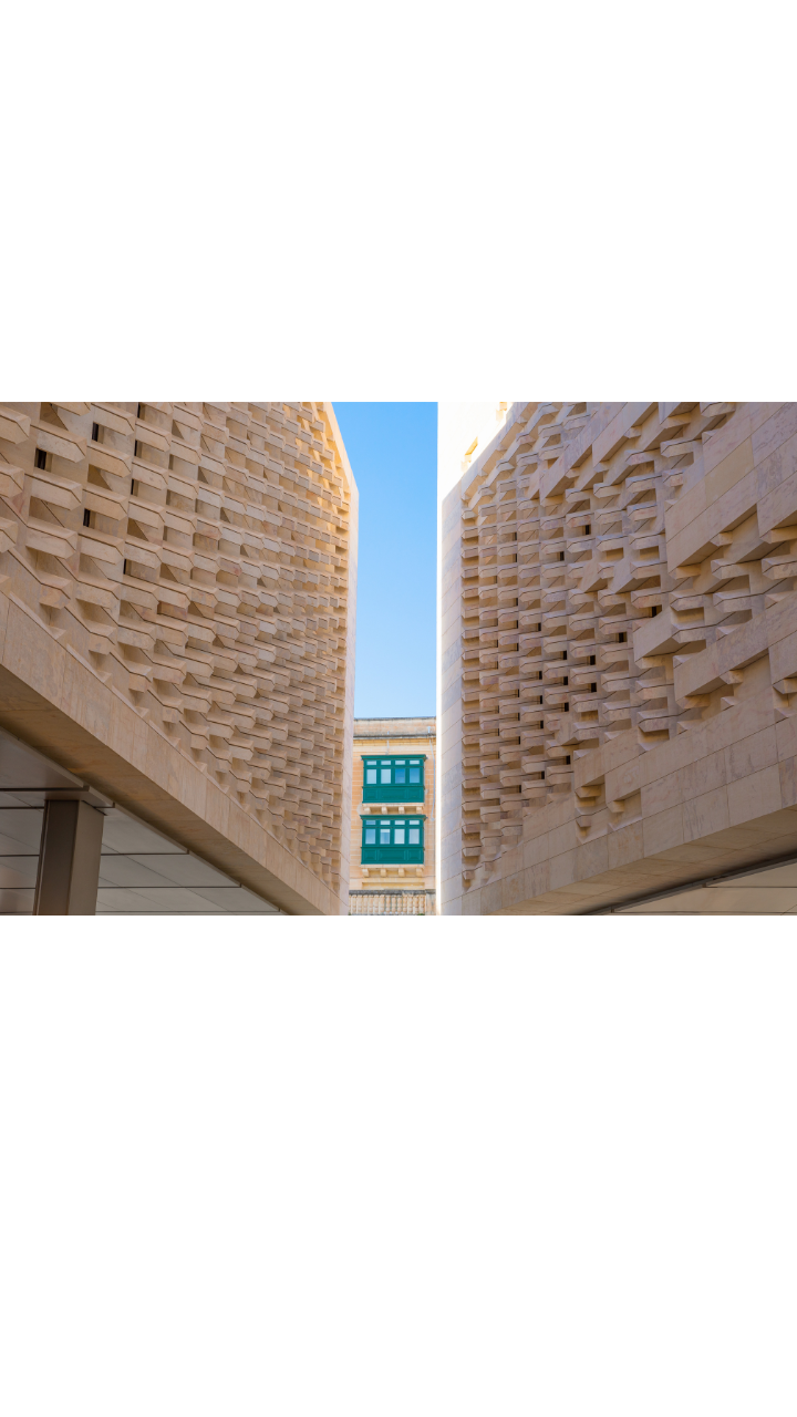 Contemporary Maltese limestone architecture framing traditional green wooden balconies against a clear blue sky.
