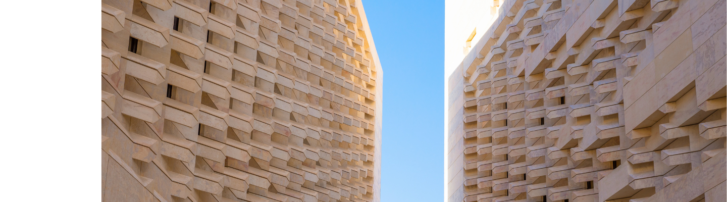 Contemporary Maltese limestone architecture framing traditional green wooden balconies against a clear blue sky.