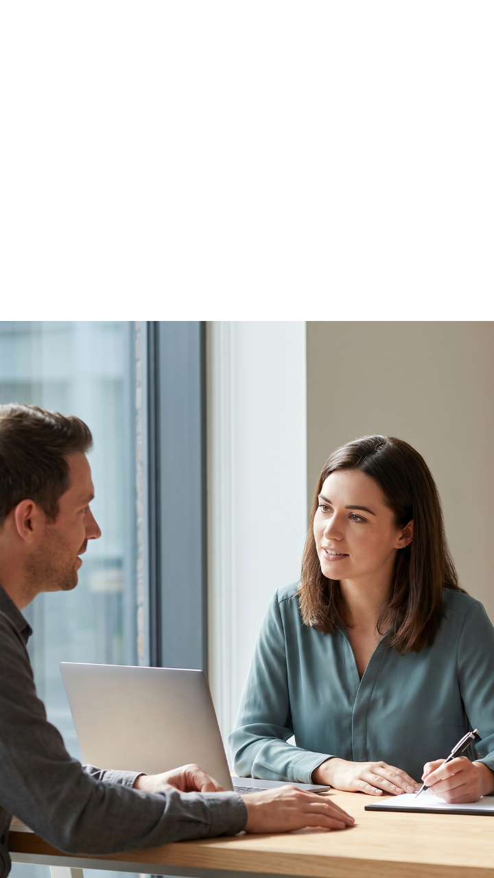 Business professionals discussing documents around a table in a bright, modern office.