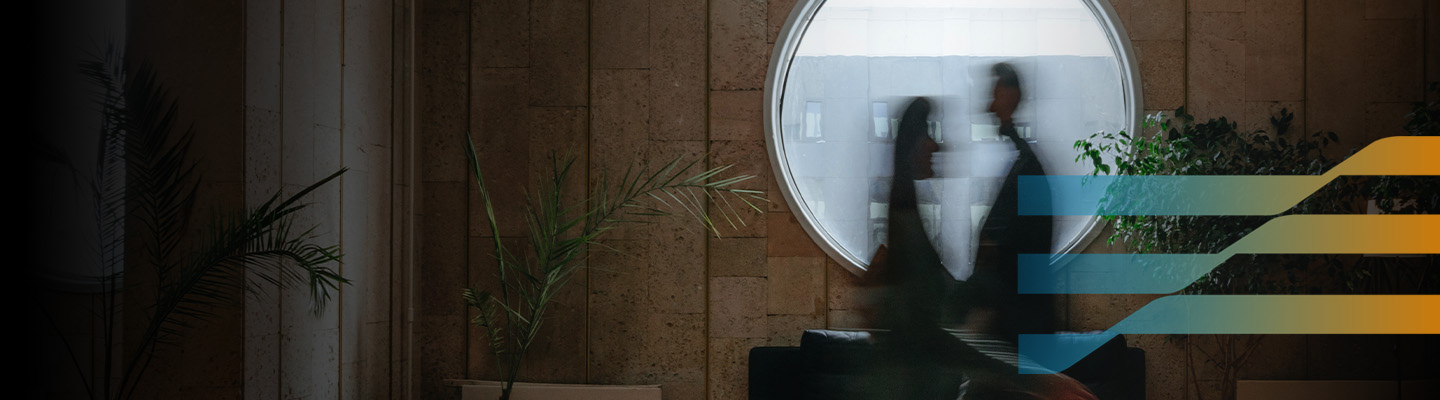 Blurred business professionals walking through a modern office with abstract digital graphics.