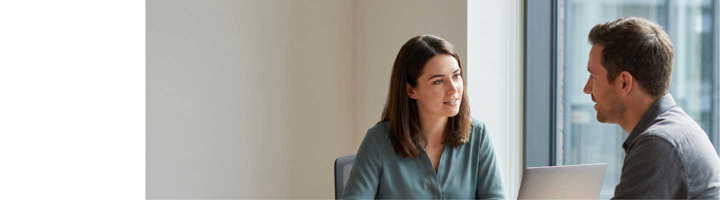 Business professionals discussing documents around a table in a bright, modern office.