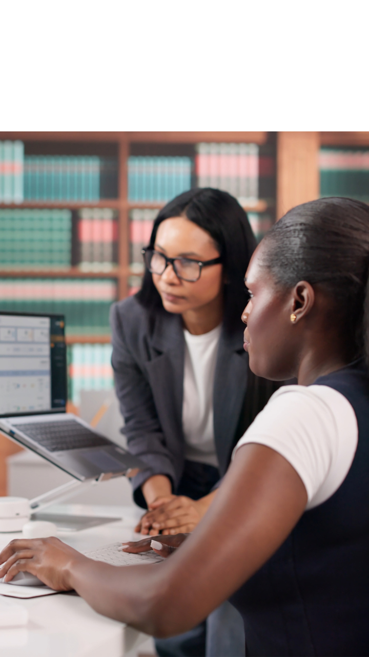 Two business professionals reviewing documents and computer screens together in an office.
