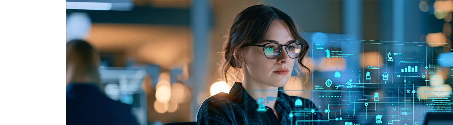 Woman working at a computer with a digital overlay showing data charts, connected processes and monitoring indicators.