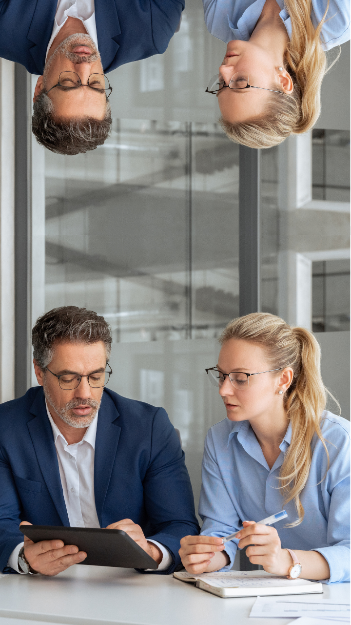 Two business professionals reviewing documents on a digital tablet during a meeting.